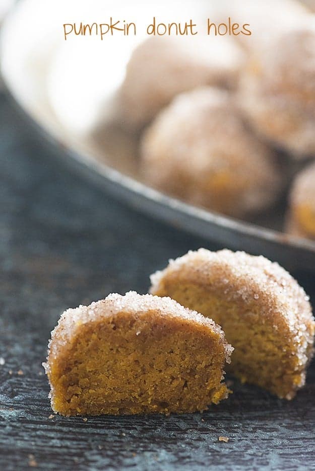 A pumpkin donut hole cut in half on a wooden table.