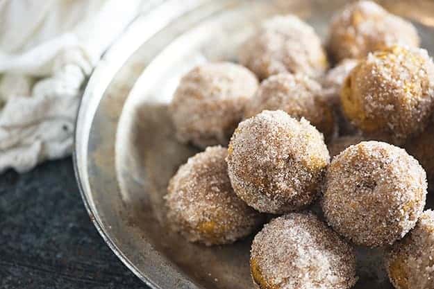 A pile of donut holes on a clear glass pie plate.