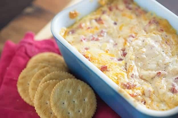 A baking dish of pimento cheese next to several Ritz crackers.
