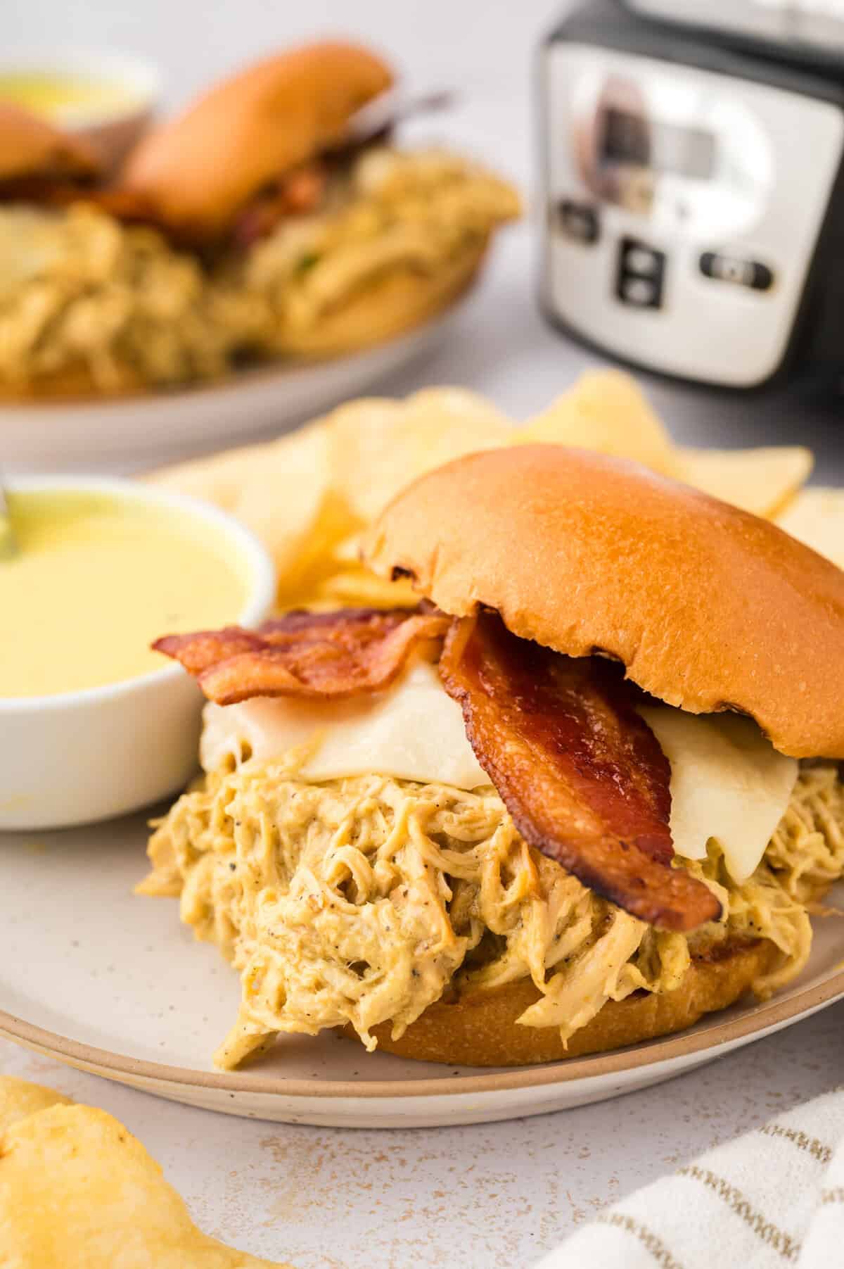 Honey mustard chicken made in the Crock-Pot® slow cooker! The chicken is so flavorful and tender! I love these sandwiches topped with bacon and swiss cheese!