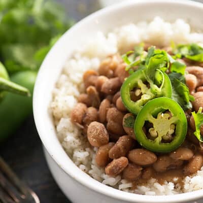 A cup of rice and beans topped with jalapenos.