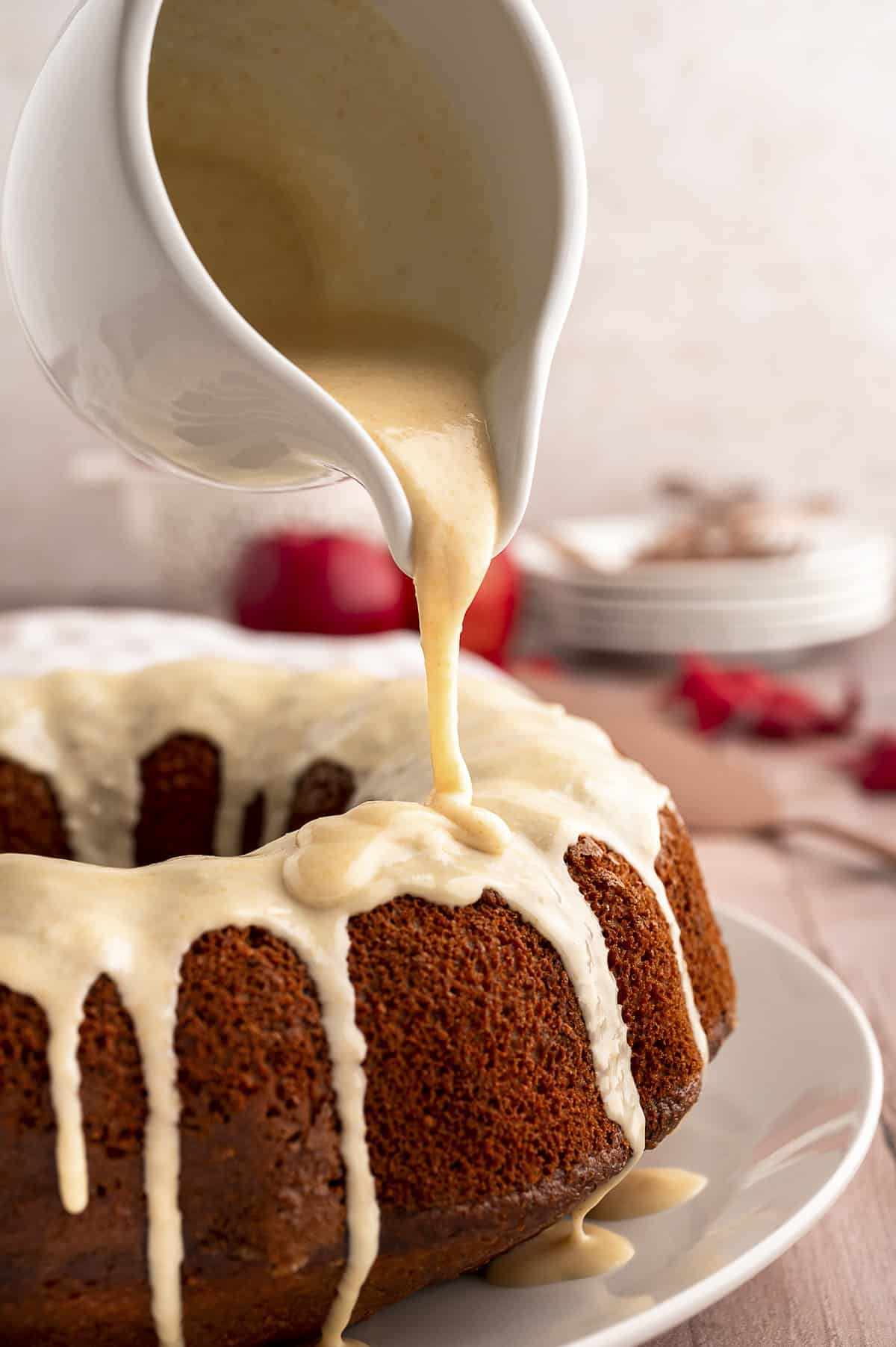 Browned butter glaze being poured over applesauce cake.