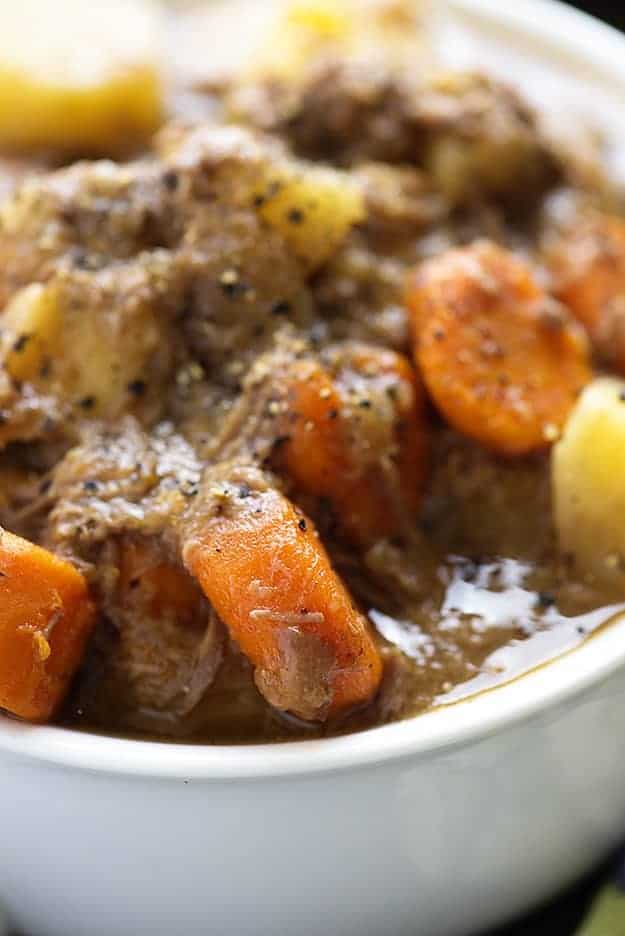 A close up of beef stew with carrot and potato pieces in it.