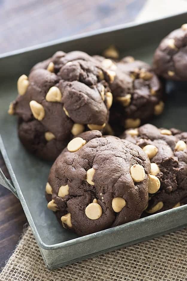 Several chocolate cookies with peanut butter chips in a metal serving tray.