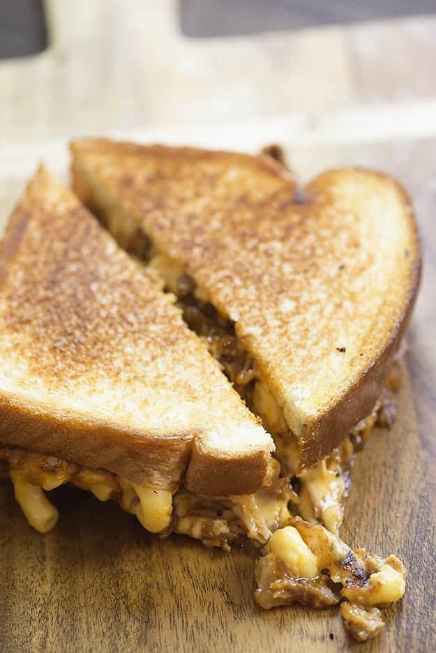 A sandwich cut in half on a wooden cutting board.