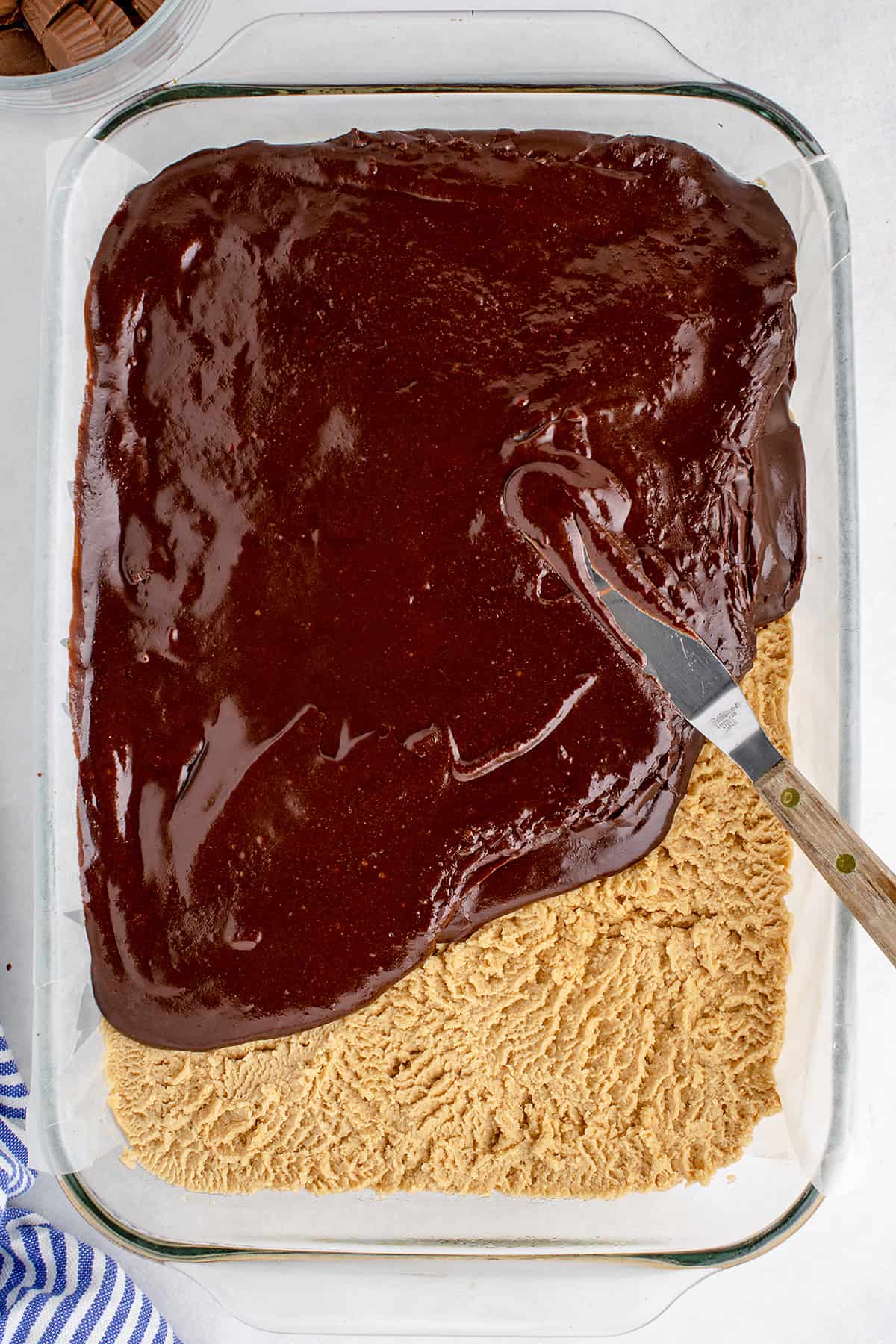 Chocolate frosting being spread over peanut butter.