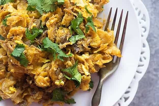 A plate of chilaquiles with a silver fork on it.