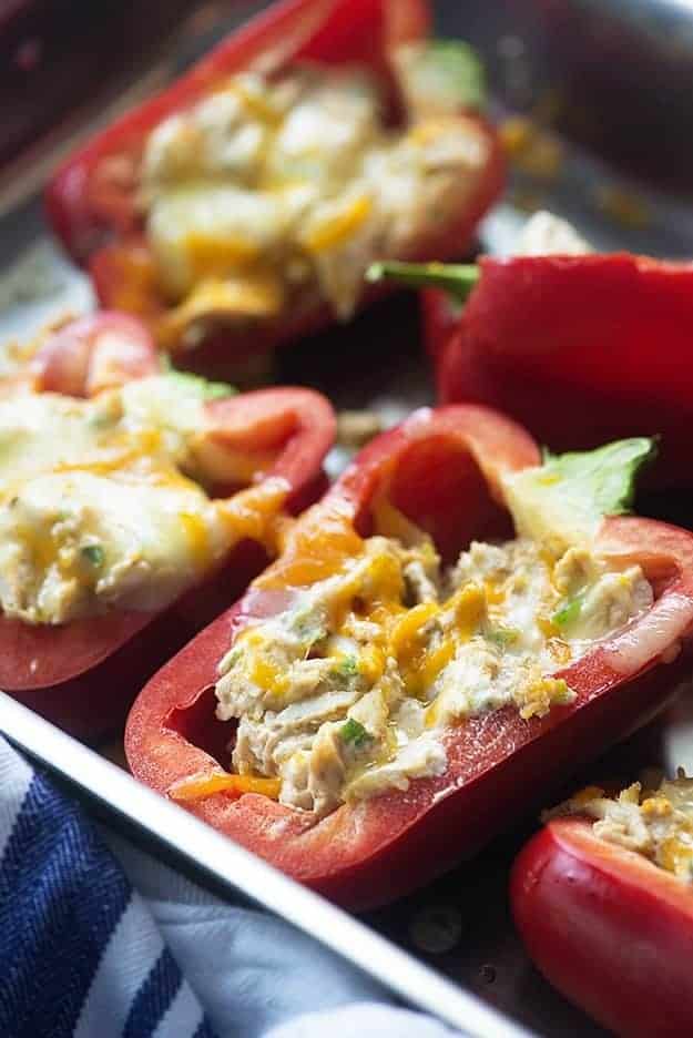 A close up of stuffed red peppers on a baking sheet.