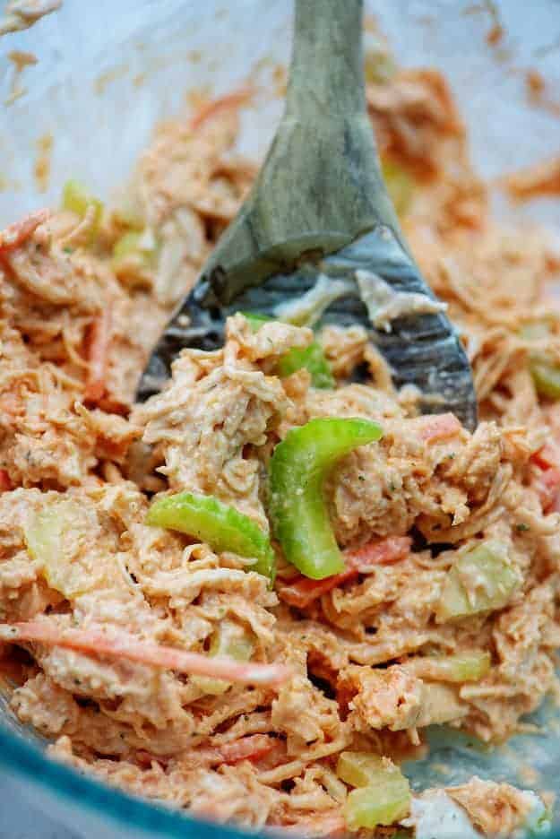 buffalo chicken salad with shredded carrots and celery in glass mixing bowl