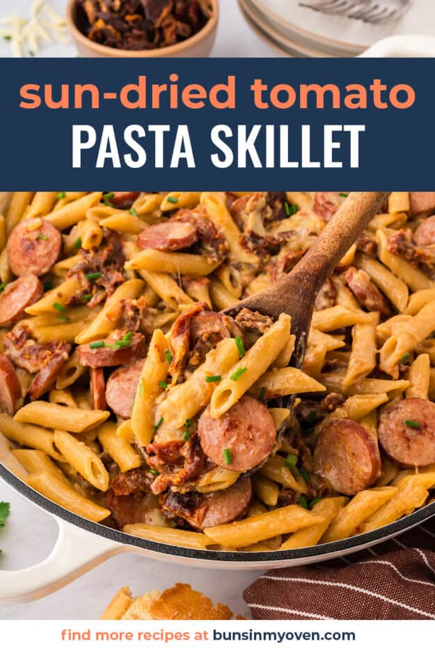 Smoked sausage pasta with sun-dried tomatoes in skillet.