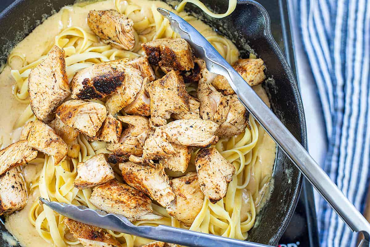 chicken and pasta in pot with Alfredo sauce.