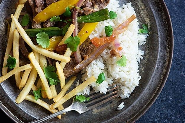 A dark plate of rice, veggies, and fries.