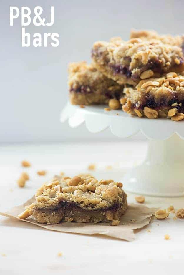 A square of peanut butter and jelly bars in front of a cake stand full of more bars.