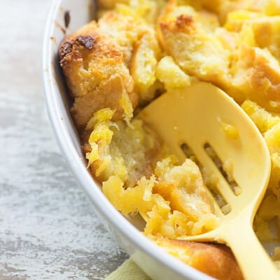 A large plastic spoon dipping into a bowl of pineapple casserole.