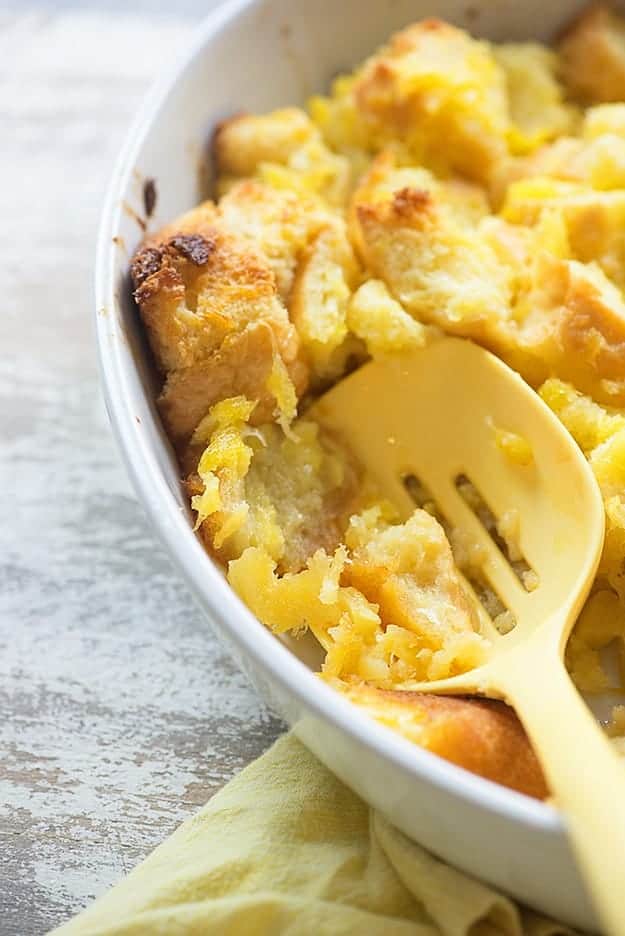 A large plastic spoon dipping into a bowl of pineapple casserole.