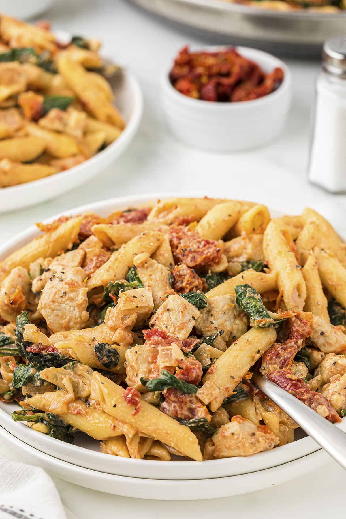 Chicken florentine pasta on small white plate.