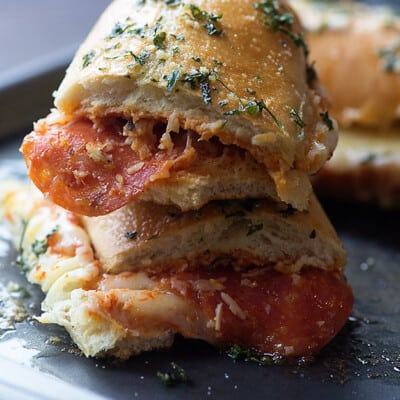 Two pieces of french bread pizza sandwiches on a baking sheet.