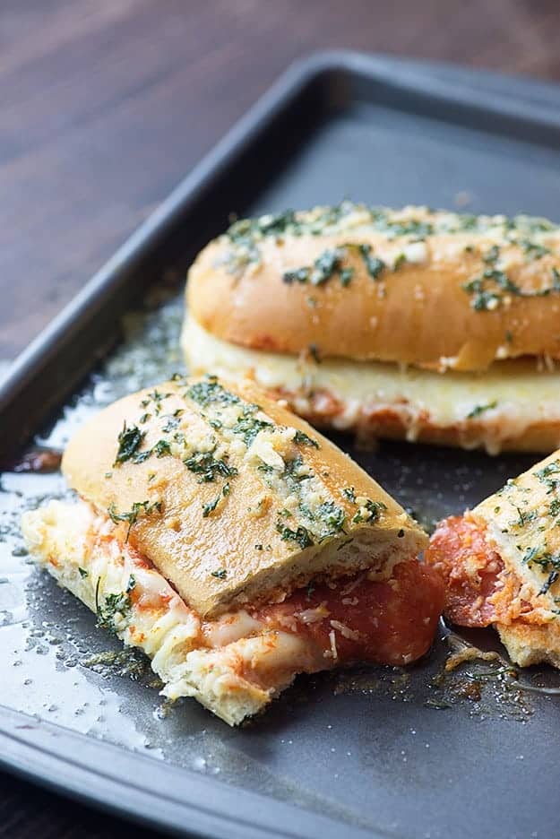 French bread pizza sandwiches on a cutting board.