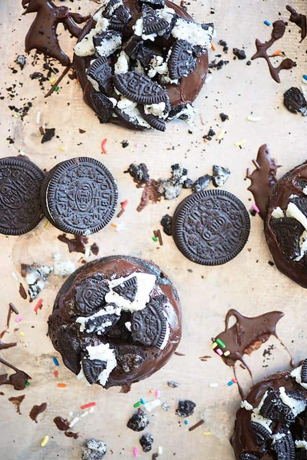 Chocolate donuts and oreos on a plastic cutting board.