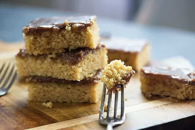 A fork taking a bite out of a piece of peanut butter cake.