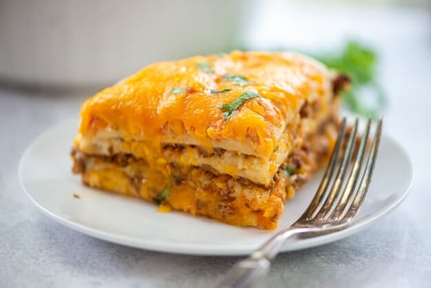 burrito casserole on white plate with vintage fork.