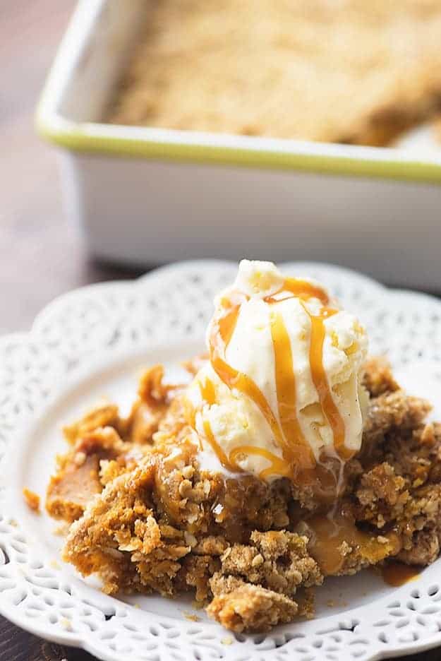 A white plate of pumpkin cobbler topped with ice cream.