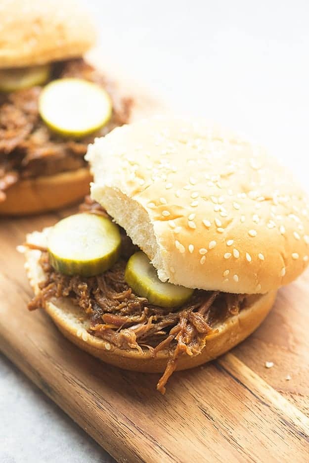 A shredded beef sandwich on a wooden cutting board.