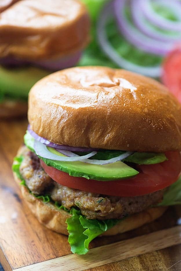 A turkey burger with lettuce, tomato, onion, and avocado.