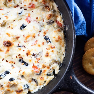 Cheesy olive dip in a cast iron skillet.