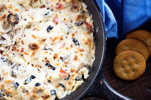 Cheesy olive dip in a cast iron skillet.