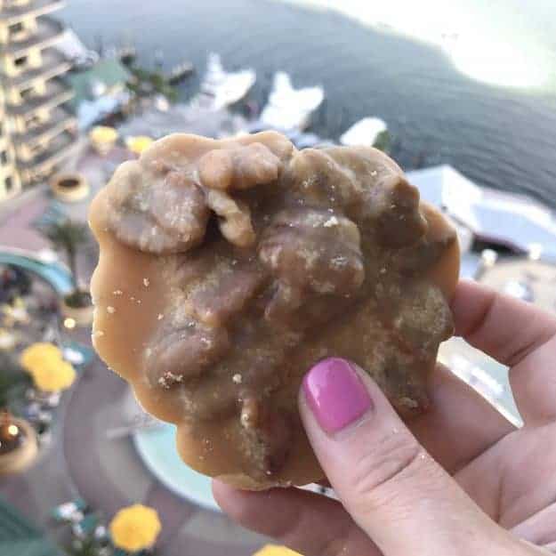 A woman holding up a turtle dessert over the balcony of a tall hotel.