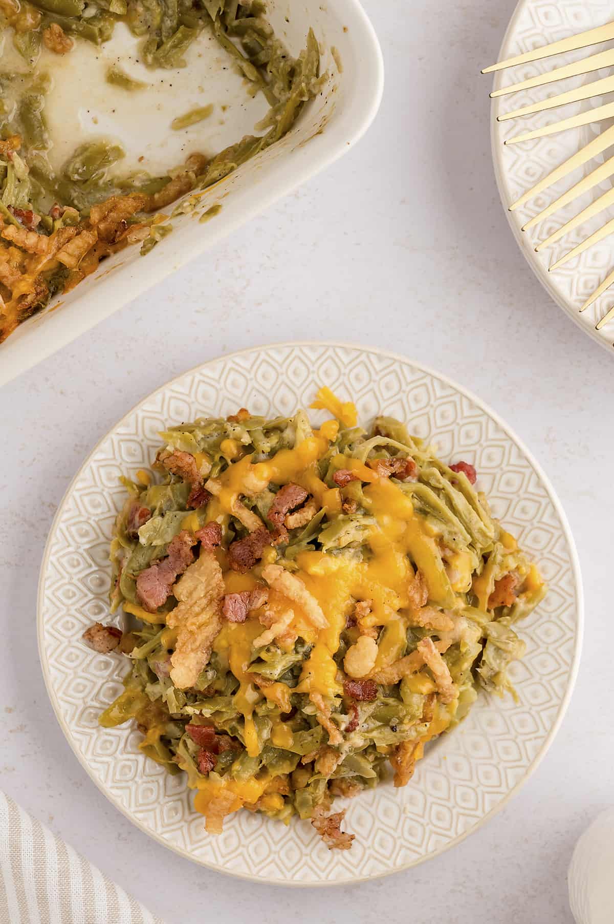 Overhead view of green bean casserole with bacon on whitep late.