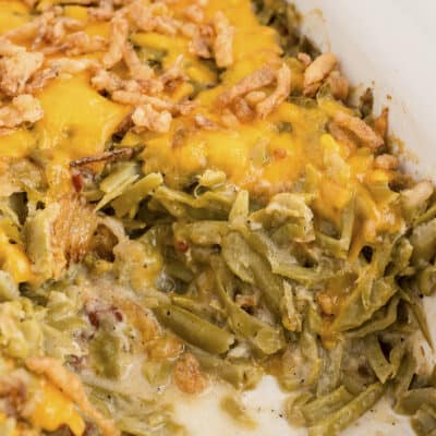 Green bean casserole with bacon in white baking dish.