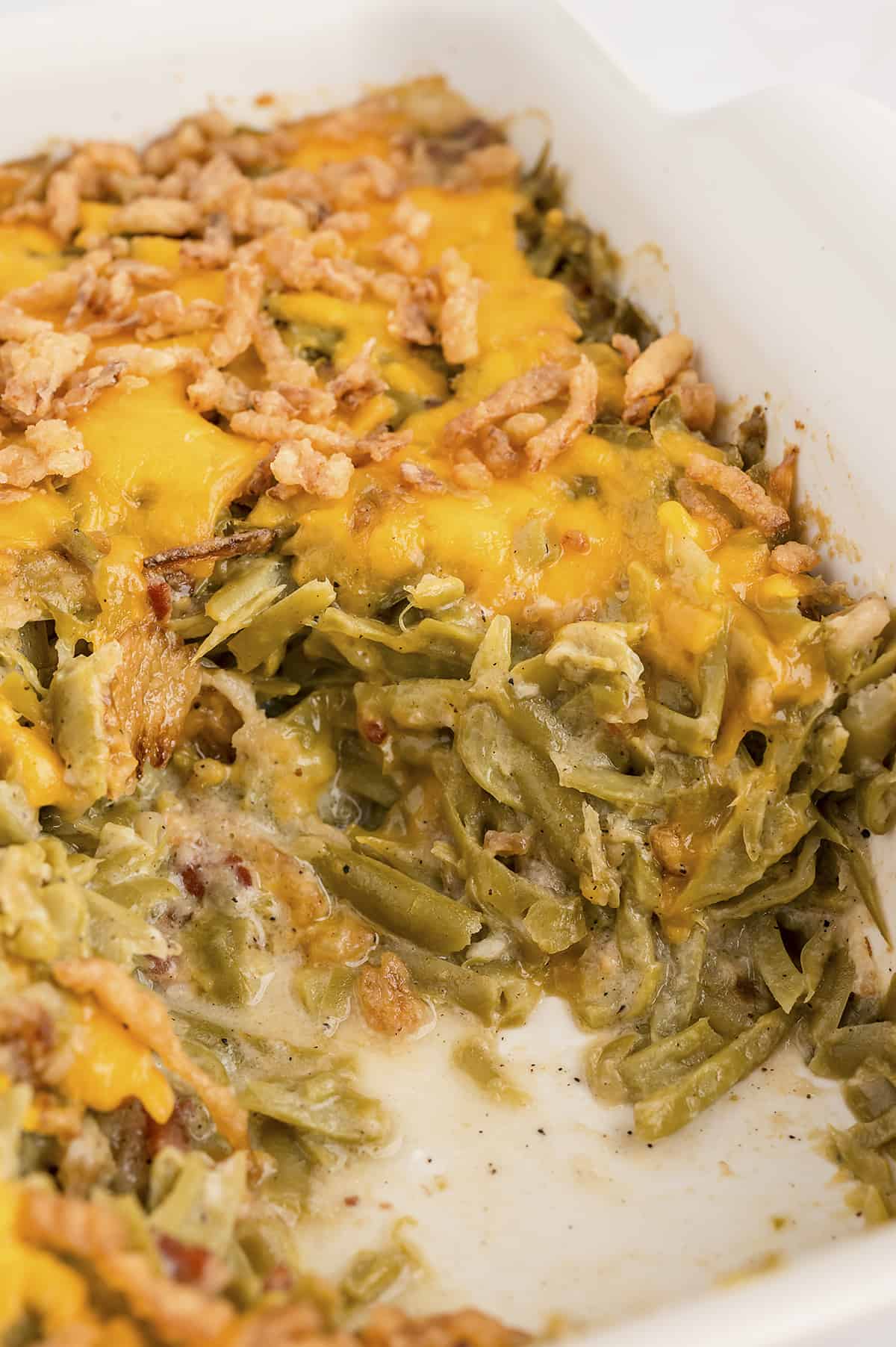 Green bean casserole with bacon in white baking dish.