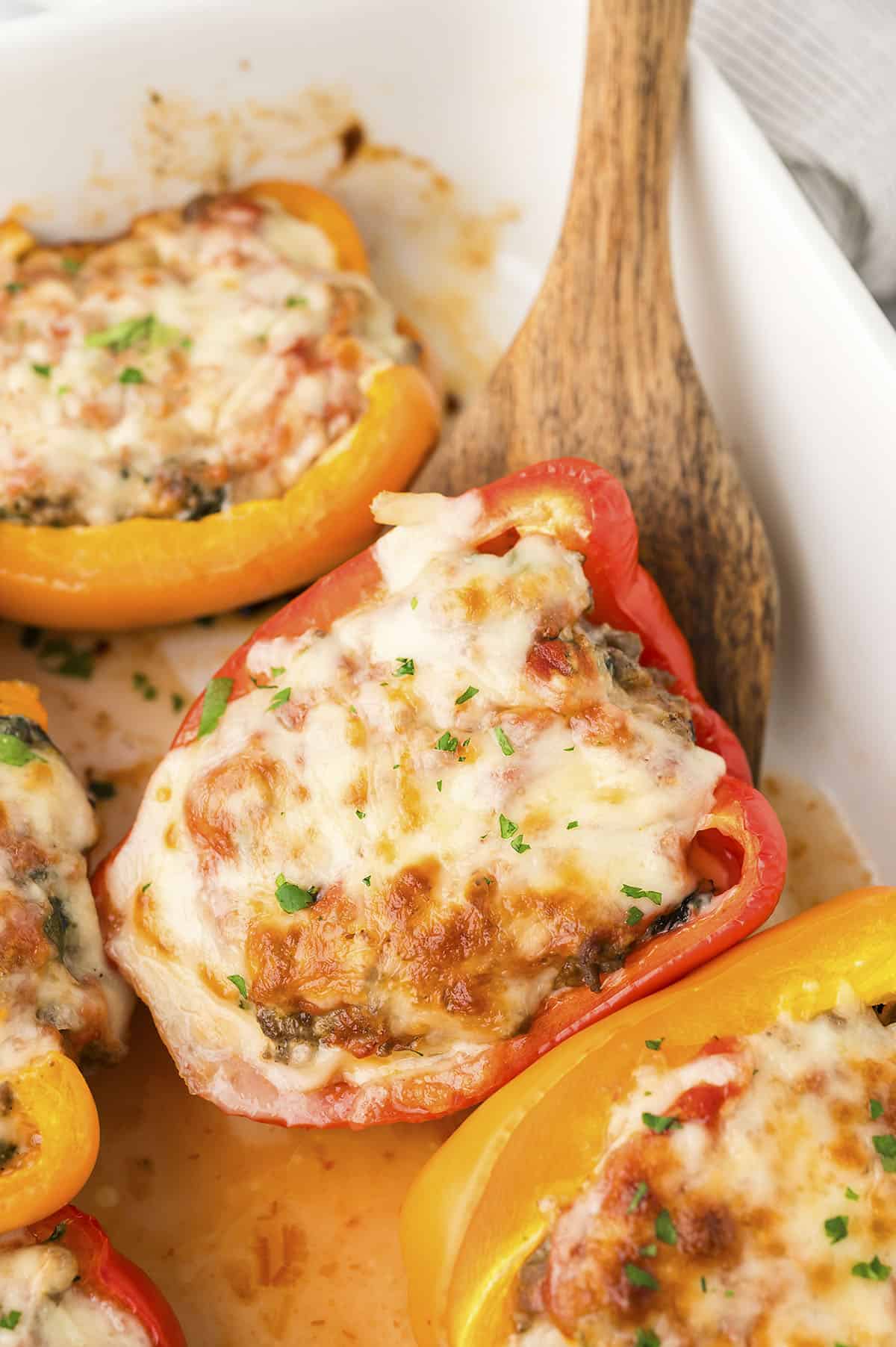 Keto stuffed pepper in baking dish with wooden spoon.
