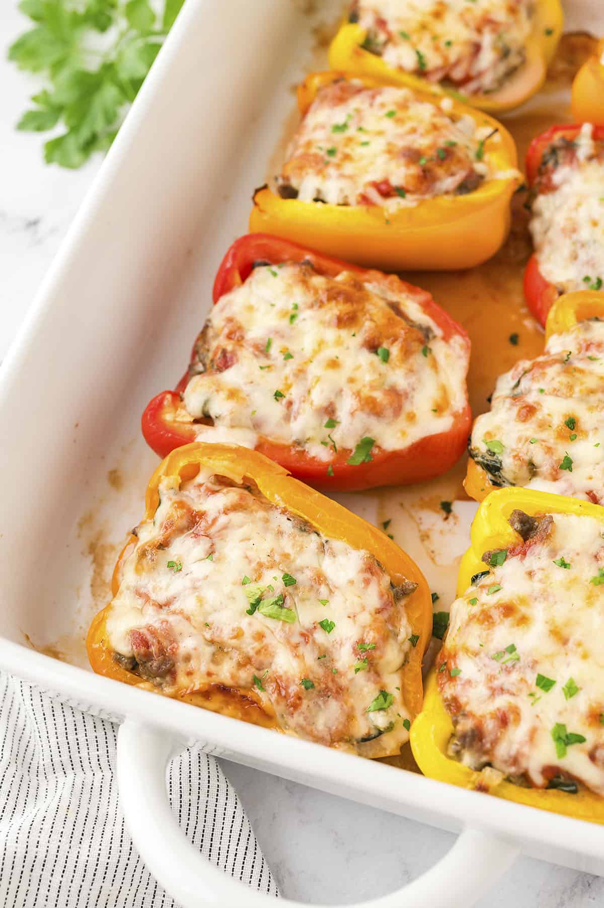 Lasagna stuffed peppers in white baking dish.