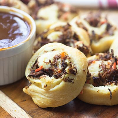 Pot roast pinwheels stacked up on a cutting board.