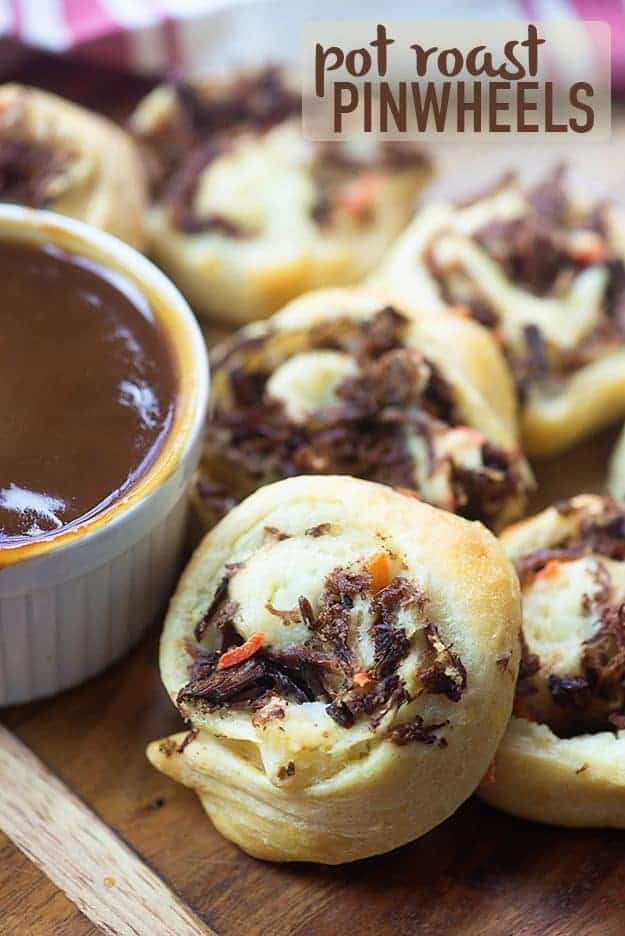 A pile of pinwheels next to a dish of sauce.