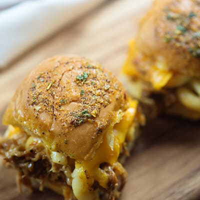 A couple pulled pork sliders on a cutting board.