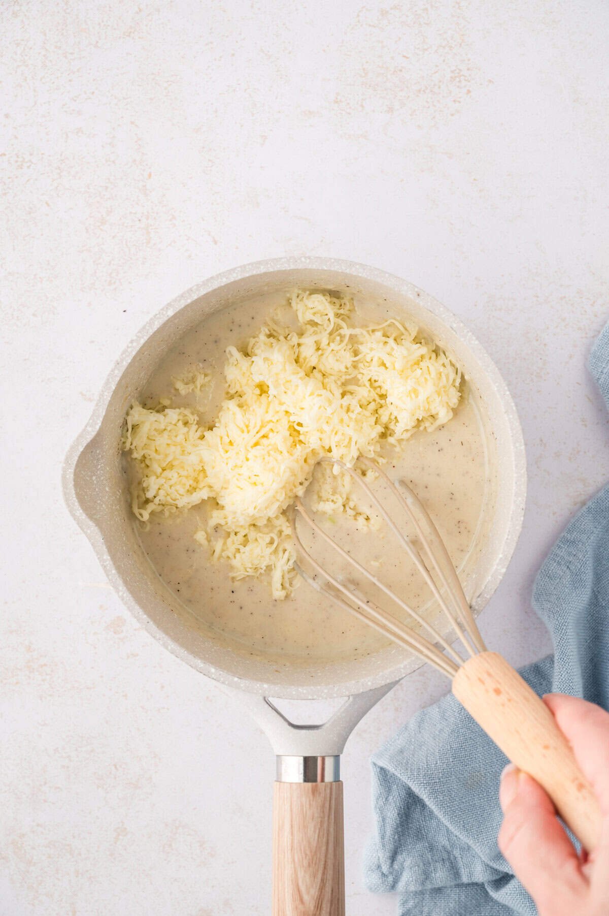 Cheese being whisked into sauce.