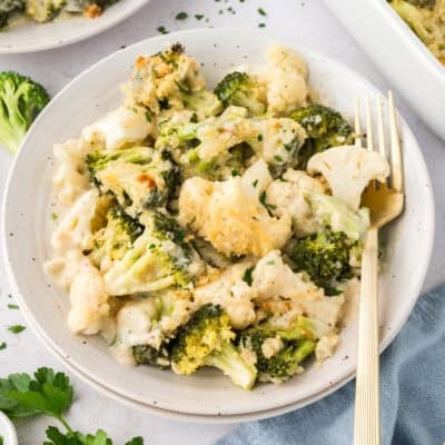 Broccoli cauliflower gratin on small white plate with fork.