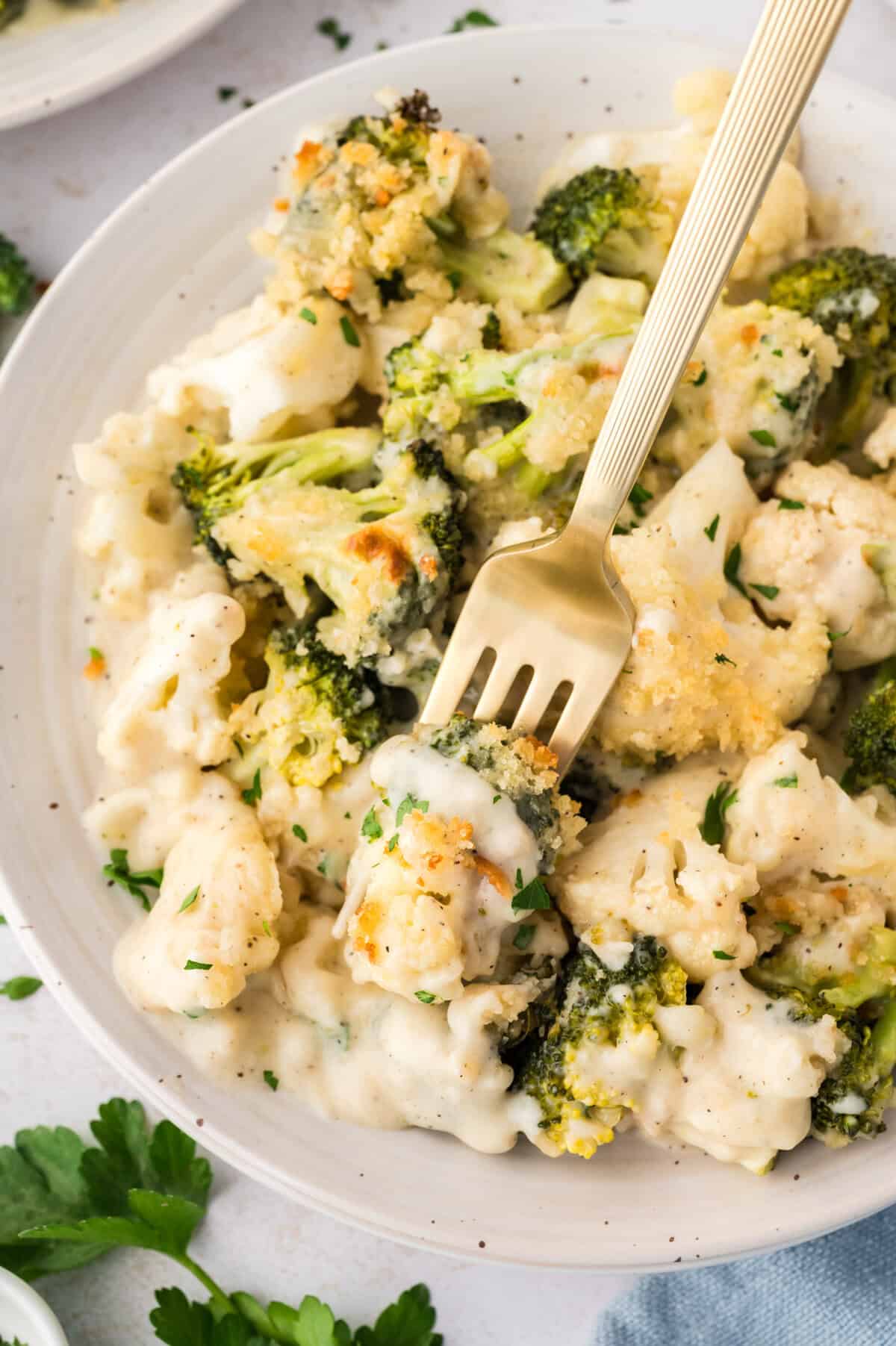 Cauliflower and broccoli au gratin on white plate with a fork.