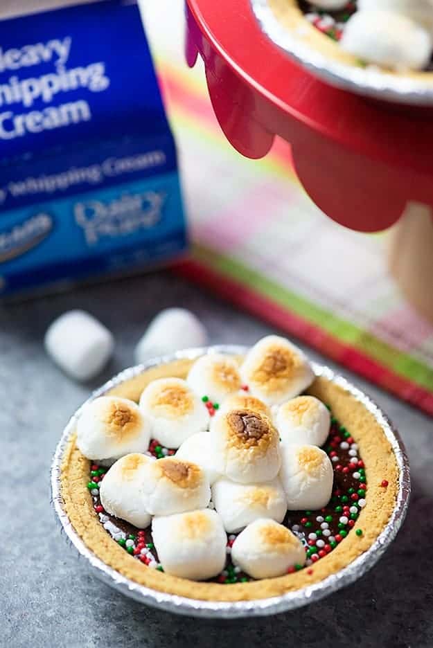 A close up of a smores pie in front of a box of whipping cream.