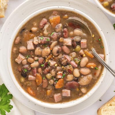 Instant Pot ham and bean soup in white bowl with vintage spoon.