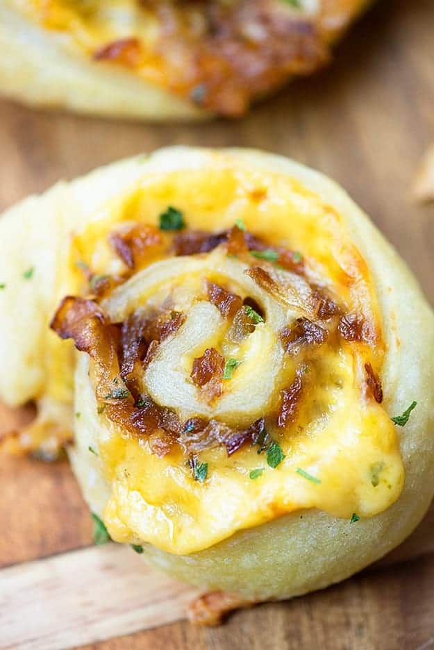 A cheese and onion pinwheel pastry on a cutting board.