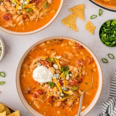Bowl full of buffalo chicken chili topped iwth sour cream and cheddar.