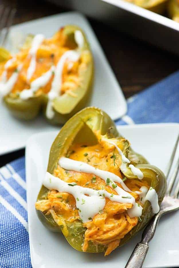 Chicken stuffed peppers on white plates.