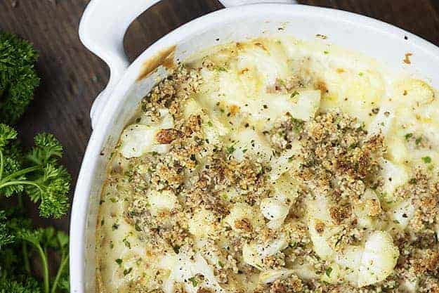 Cheesy cauliflower bake has a low carb cheese sauce in white pot.