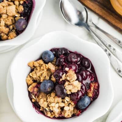 Overhead view of blueberry crisp in small white serving dish.