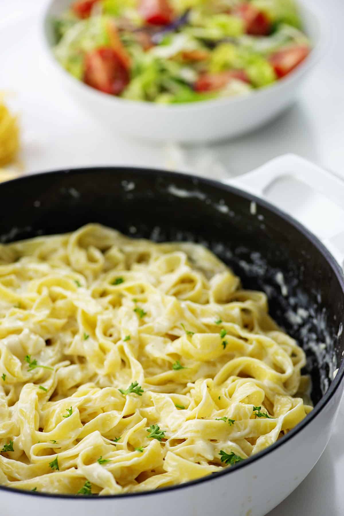 homemade alfredo sauce recipe over fettucine in pan